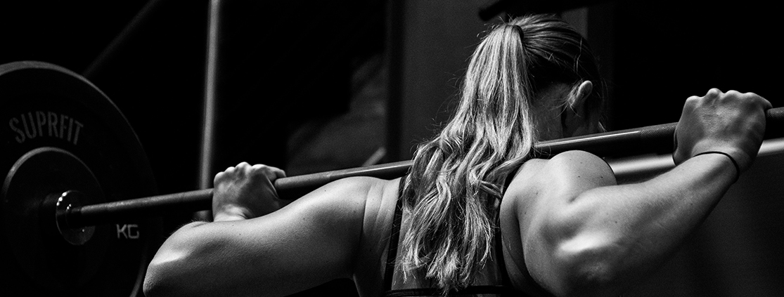 A woman squat lifting a barbell.